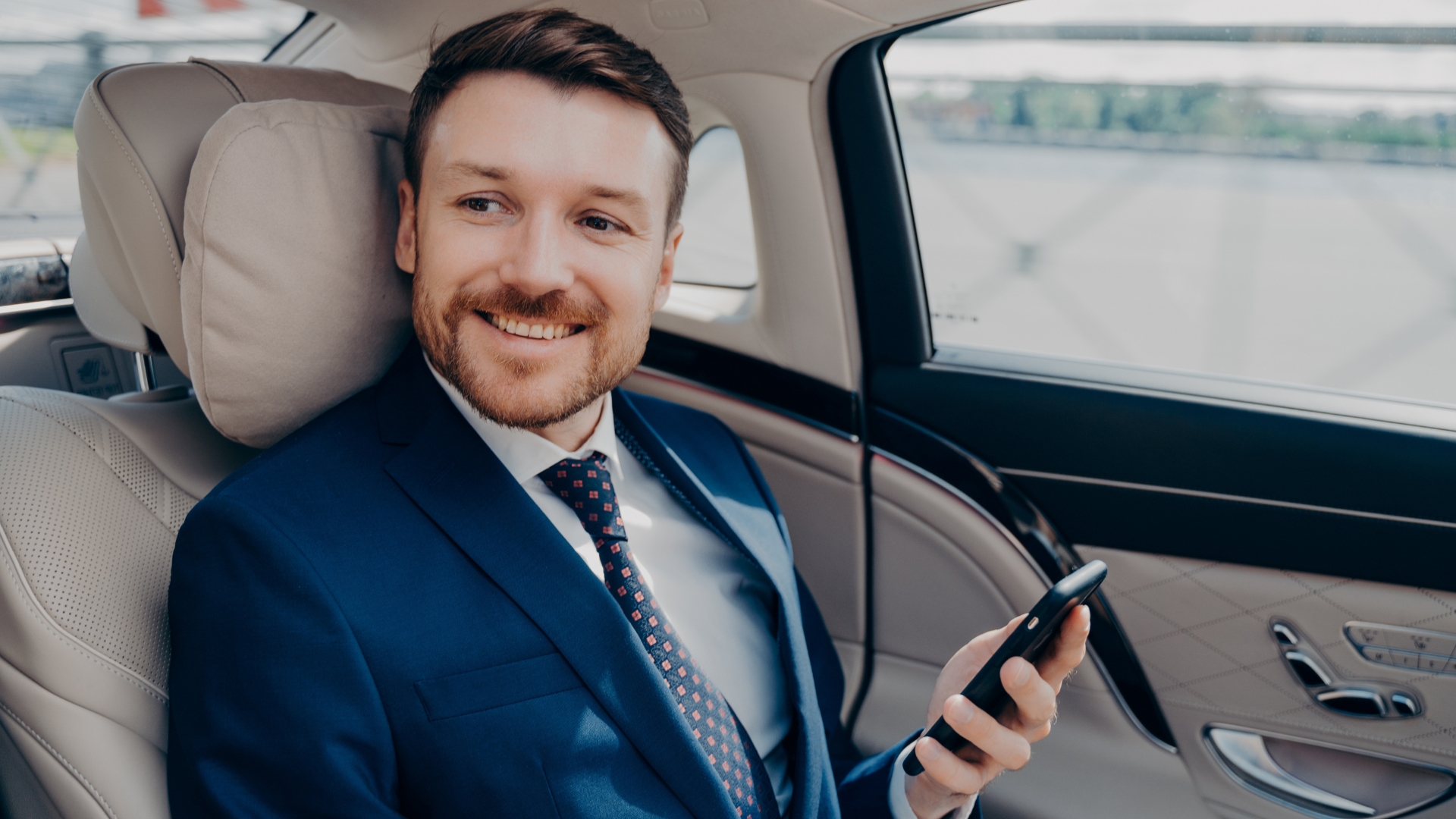 Un businessman assis à l'arrière d'une voiture haut de gamme avec chauffeur.